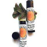Lip balm tubes with white labels, black caps, and green leaves on white background