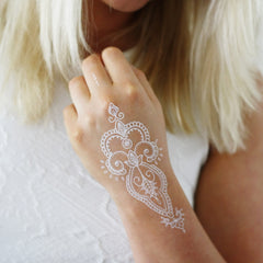 Close-up of white henna tattoo design on forearm with intricate boho patterns, showcasing safe temporary skin art application