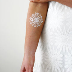 Close-up of white henna tattoo on forearm showcasing intricate boho mandala design with natural skin texture
