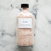 Facial Cleansers pink powder in glass bottle with ANITAKO label on marble surface