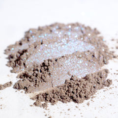 Close-up of taupe eyeshadow with silver and iridescent blue shimmer in compact pan