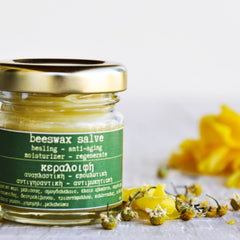 Beeswax salve jar with gold lid, green label, and yellow salve inside, with flowers