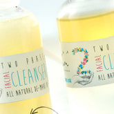 Facial cleanser bottles with yellow liquid, white labels, and floral design with Elixirium text