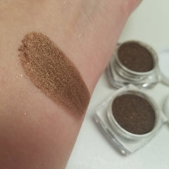 Close-up of warm gingerbread brown shimmer eye shadow in sifter jar, showcasing rich cocoa tones and metallic finish