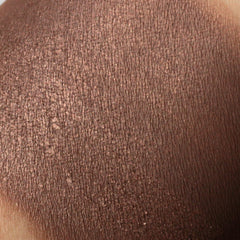 Close-up of bronze brown mineral eyeshadow with shimmering flecks in compact pan