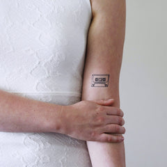 Close-up of cassette tape temporary tattoo sheet with 90s design, showing skin-safe adhesive details