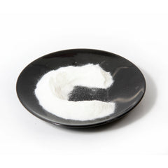 Side view of amber glass bottle with dropper containing golden vitamin C serum on marble surface