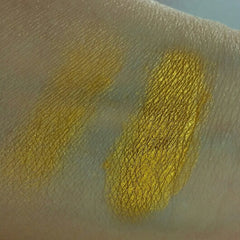Yellow eyeshadow swatch on skin, metallic gold color, textured appearance, applied on arm