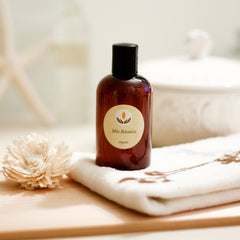 Brown bottle with black cap, Mia Botanica label, on white towel with flower