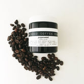 Coffee scrub jar with white lid, black jar, and coffee beans with "Damn Good Coffee Scrub" text