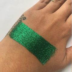 Green glitter swatch on hand, showing sparkle and texture, used for makeup application