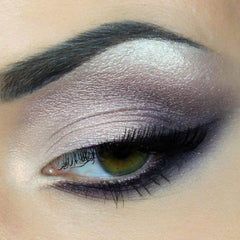 Eye makeup with silver and purple eyeshadow, black mascara, and dark eyebrows on an eye