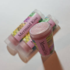 Lip balm tubes with pink, glittery balm and "Mermaid Kiss" text on pink labels