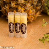Lip balm tubes with yellow balm, clear plastic, and oval labels with text on wooden surface