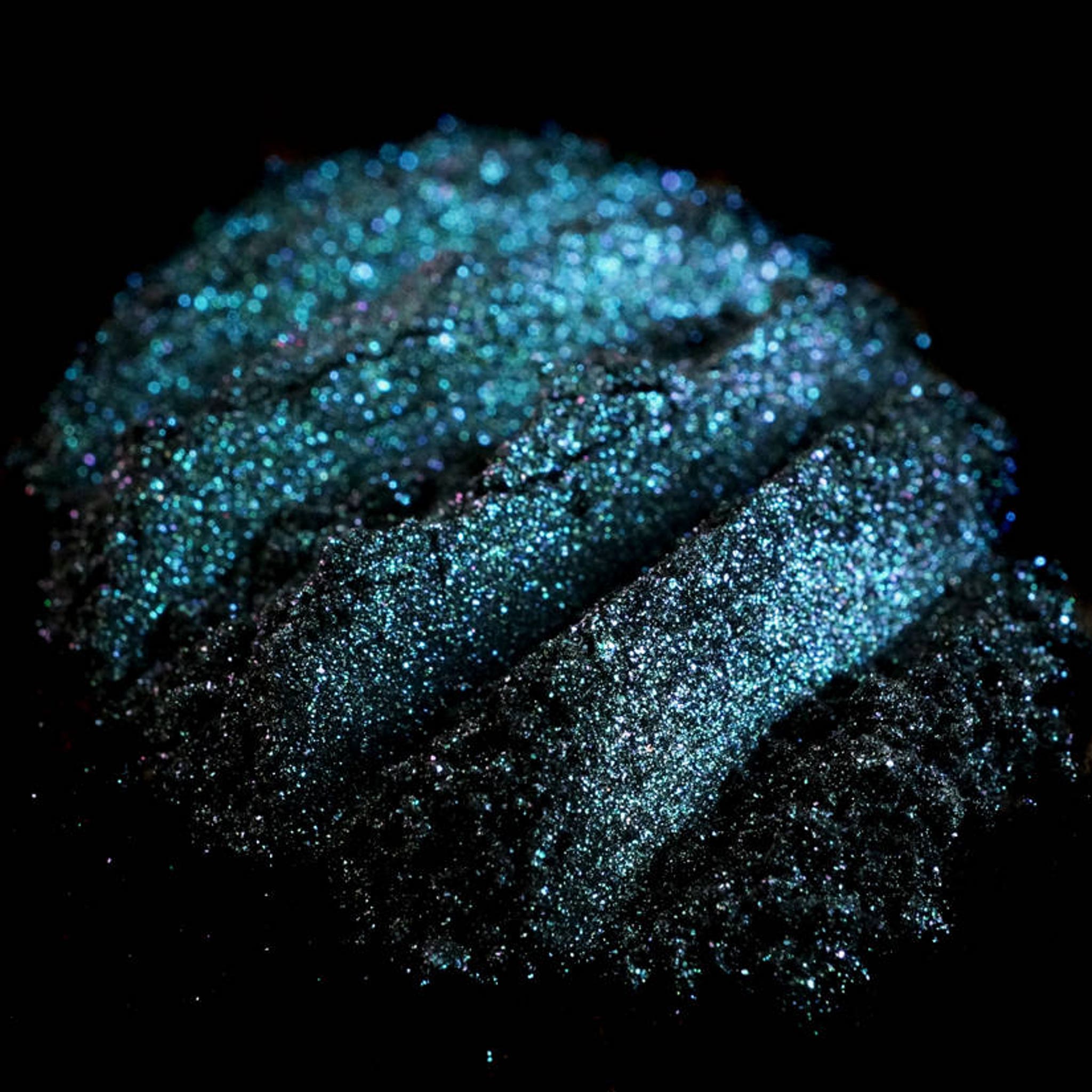 Close-up of iridescent teal eyeshadow with colorshifting glitter in round compact from vegan mermaid collection