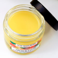 Herbal butter balm cleanser in glass jar with yellow balm, black lid, and label
