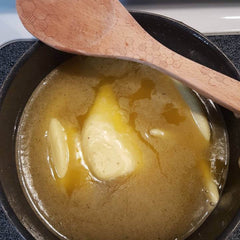 Butter melting in black pan with wooden spoon, yellow and brown colors