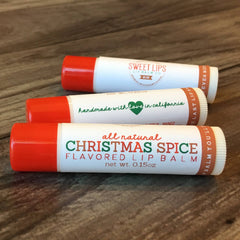Lip balm tubes with red caps, white tubes, and printed text, Sweet Lips and Christmas Spice flavors