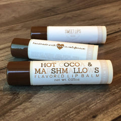 Lip balm tubes with brown caps, white labels, and visible text including "SWEET LIPS" and "HOT COCOA & MARSHMALLOWS
