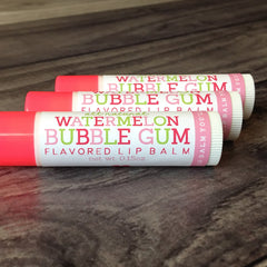 Lip balm tubes with pink, white, and green text on white labels, watermelon and bubble gum flavors visible