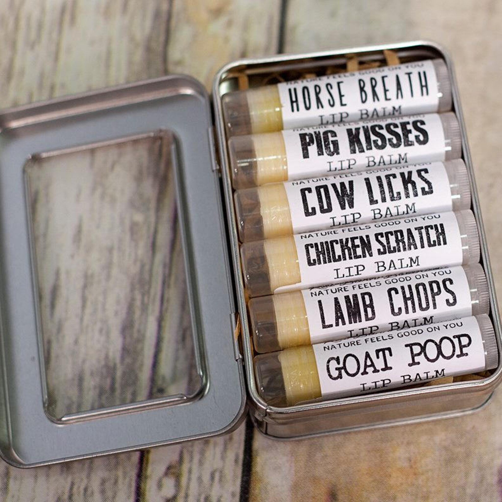 Lip balm set in metal tin with white labels and humorous text on wooden surface