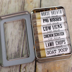 Lip balm set in metal tin with white labels and humorous text on wooden surface