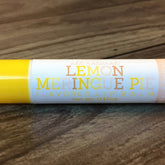 Lip balm tube with yellow and white, "Lemon Meringue Pie" text, on wood grain background