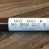 Lip balm tube with brown and white label, wooden background, "Hot Cocoa & Marshmallows" text