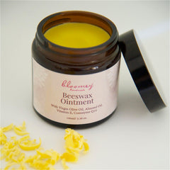 Beeswax ointment in a brown glass jar with yellow contents and black lid, "bloomey handmade" label visible