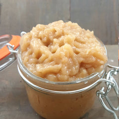 Facial cleanser in a clear glass jar with silver clasp and light brown contents