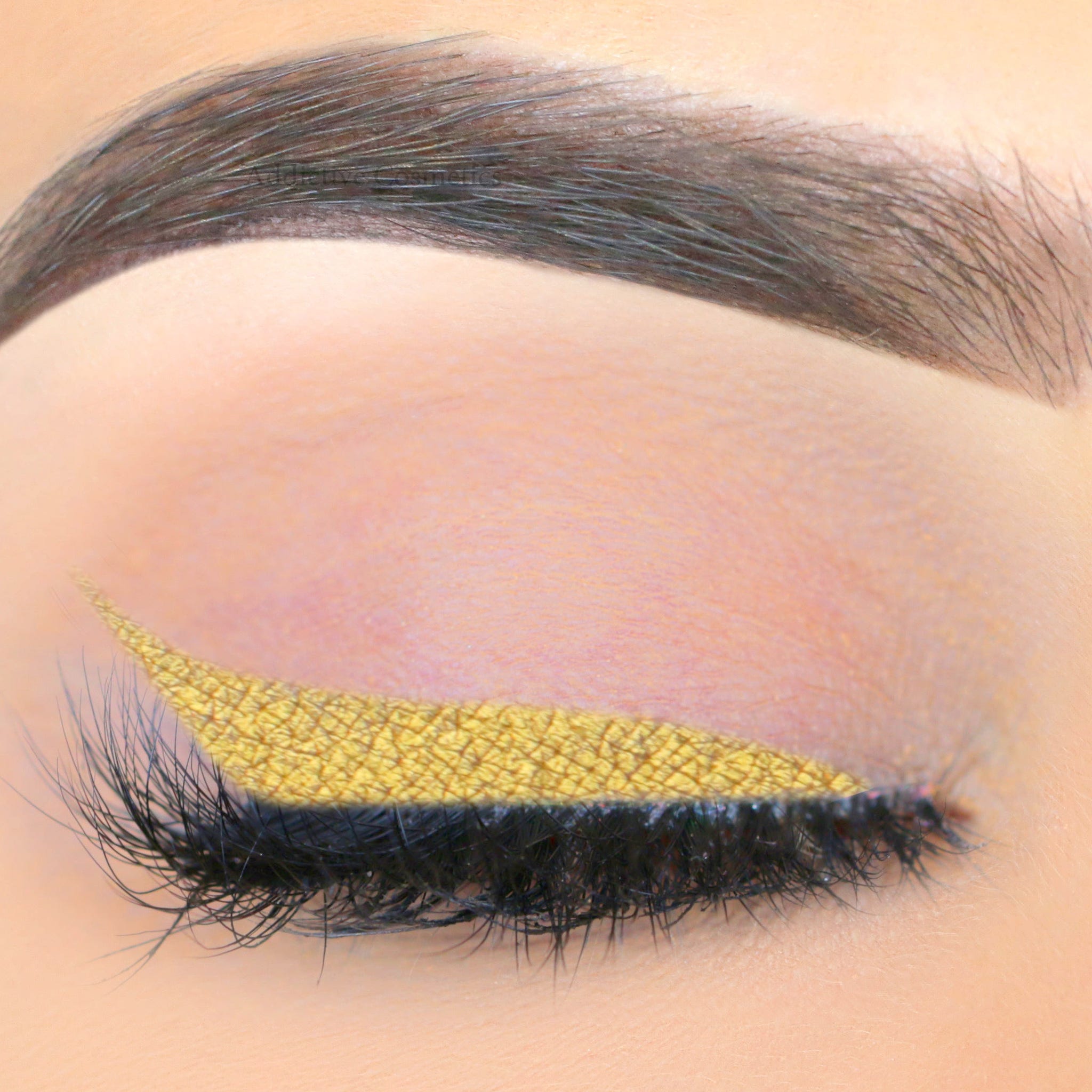 Liquid eyeliner gold metallic applied to eyelid with lashes visible
