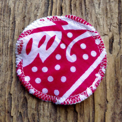 Round fabric patch with red and white pattern, white stitched trim, and polka dots on a wood surface