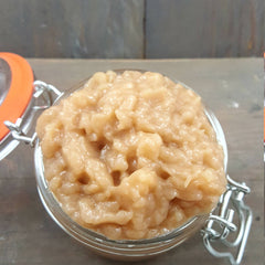 Creamy beige food in a glass jar with orange lid and silver metal clasp, on a wooden surface