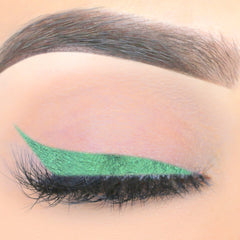 Green liquid eyeliner with winged tip on eye with black lashes and eyebrow