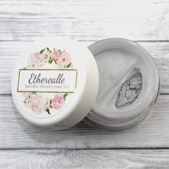 Eyelid powder with light grey color in clear jar and floral lid, Etherealle brand name visible