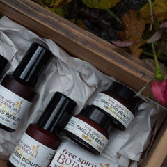 Skincare products in brown glass bottles with black lids, in a wooden box with white paper, Free Spirit Botanicals brand visible