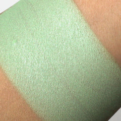 Close-up of shimmery pistachio green eyeshadow with mineral sparkle in compact pan