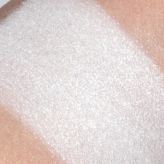 Hand applying shimmery white mineral eyeshadow with fingertip to eyelid for a frosty glow