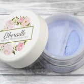 Eyeshadow powder with light blue shimmer, clear jar, and Etherealle branding on lid