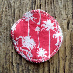 Reusable pad with red palm tree pattern, white stitching, and round shape