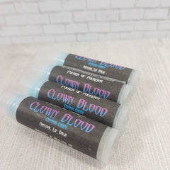 Lip balm tubes with black labels and blue/pink text, stacked on white surface, "CLOWN BLOOD" visible