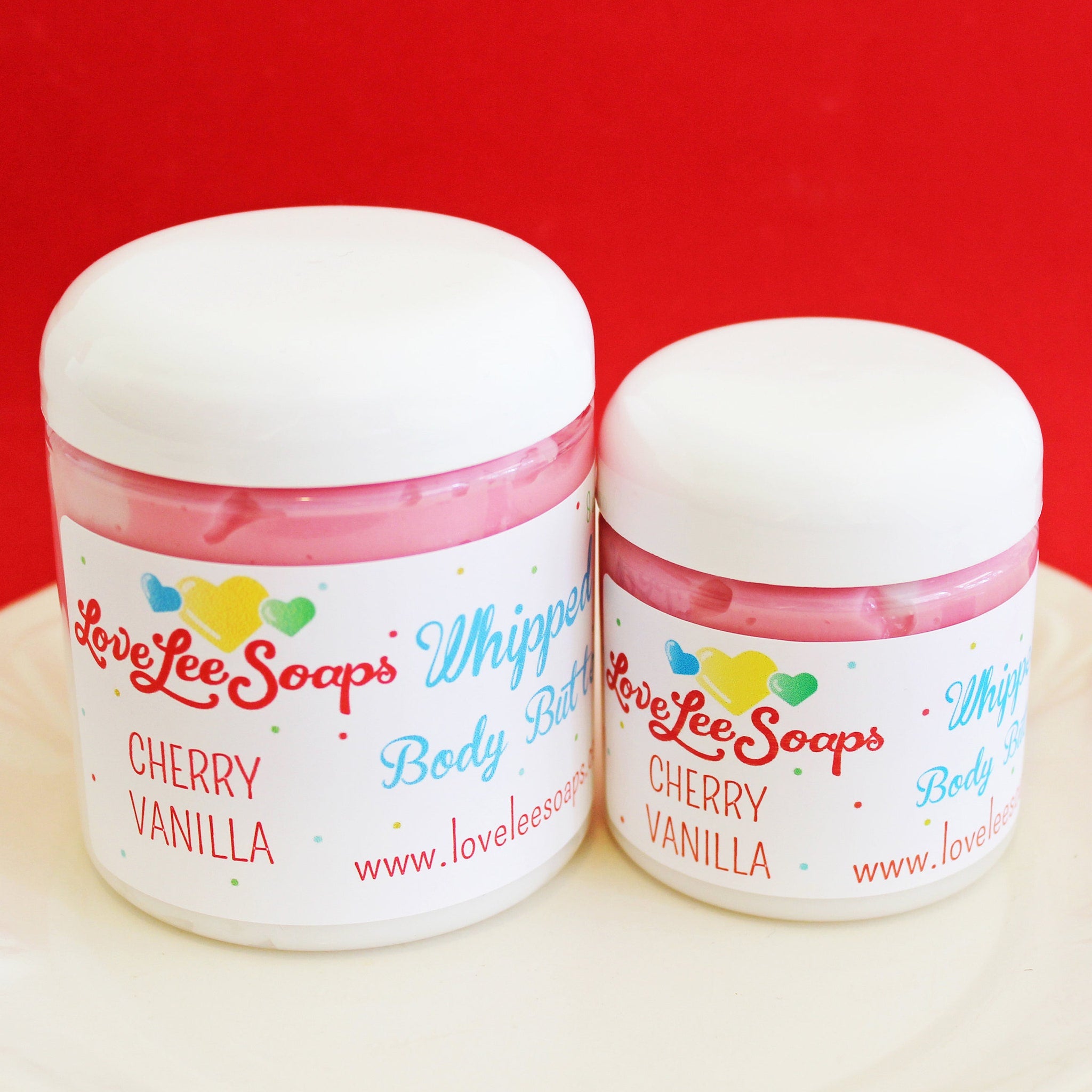 Pink glass jar of cherry vanilla whipped body butter with gold lid and vegan skincare label