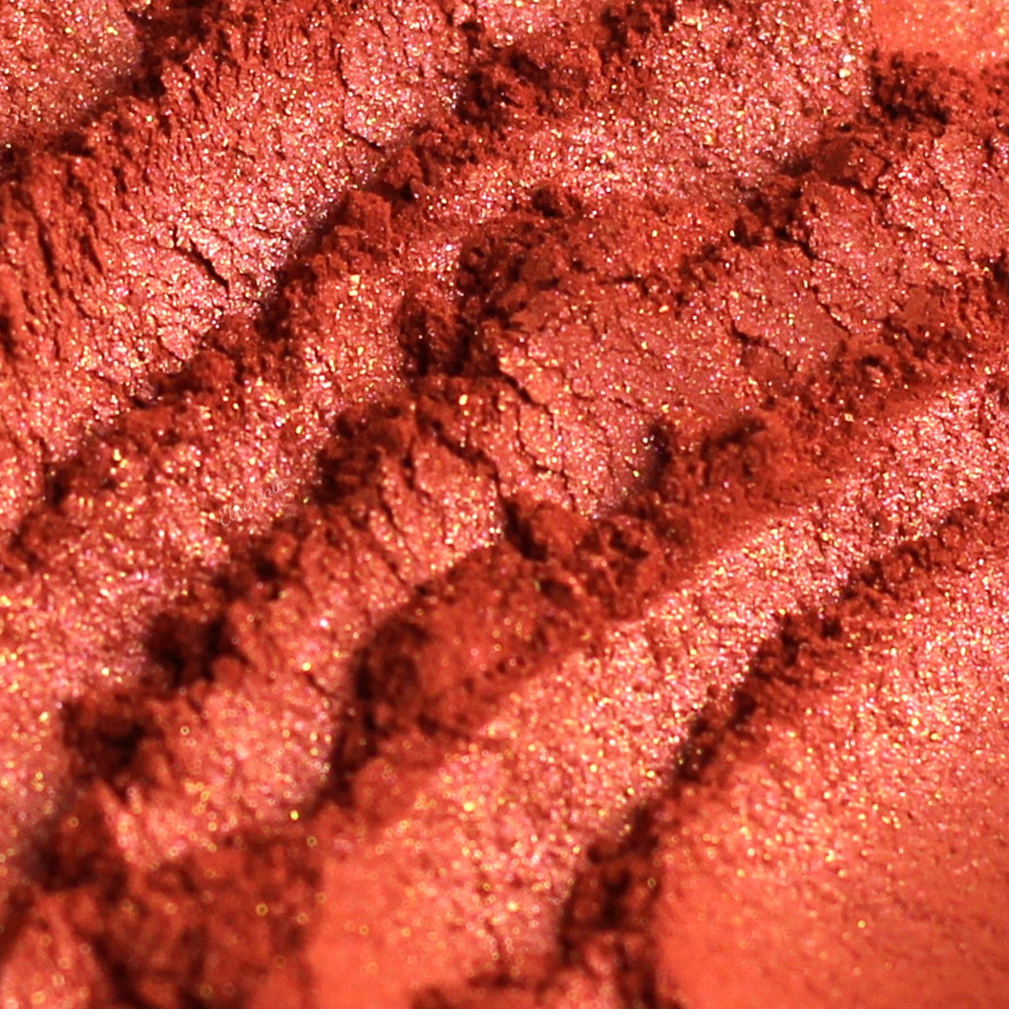 Eye shadow, coral pink duochrome powder, textured surface with glitter flecks