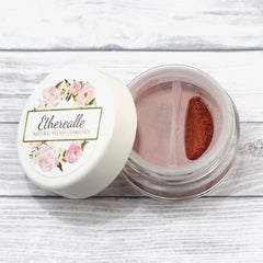 Etherealle makeup jar with white lid, floral design, and copper powder inside a clear container