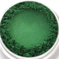 Green powder eyeshadow in a round clear container, with textured and smooth areas