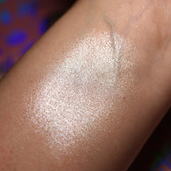 Highlighter swatch showing light iridescent shimmer on skin, with a wet look finish