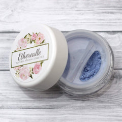 Blue powder cosmetic with white lid, floral design, and Etherealle Natural Vegan Cosmetics text visible
