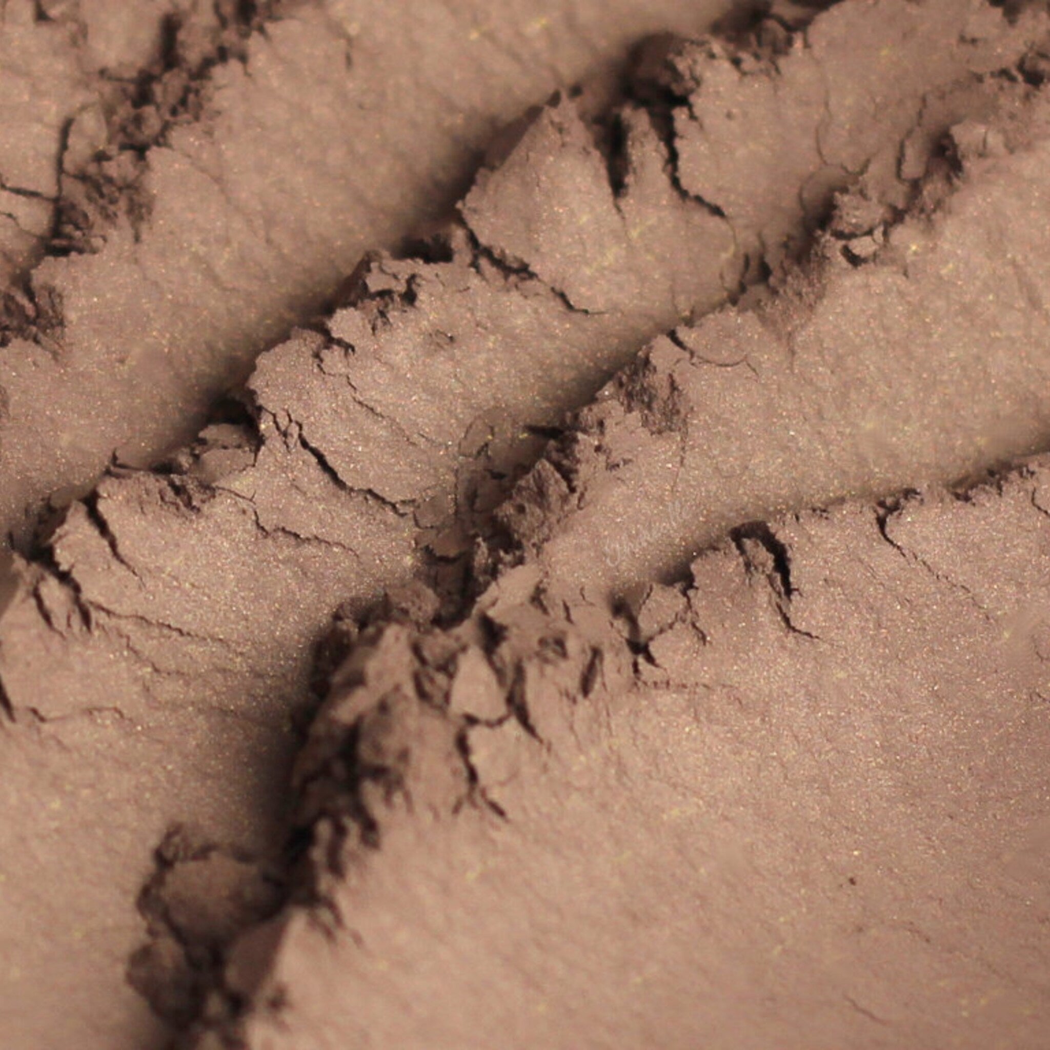 Eyeshadow powder with medium brown color and subtle shimmer, textured surface