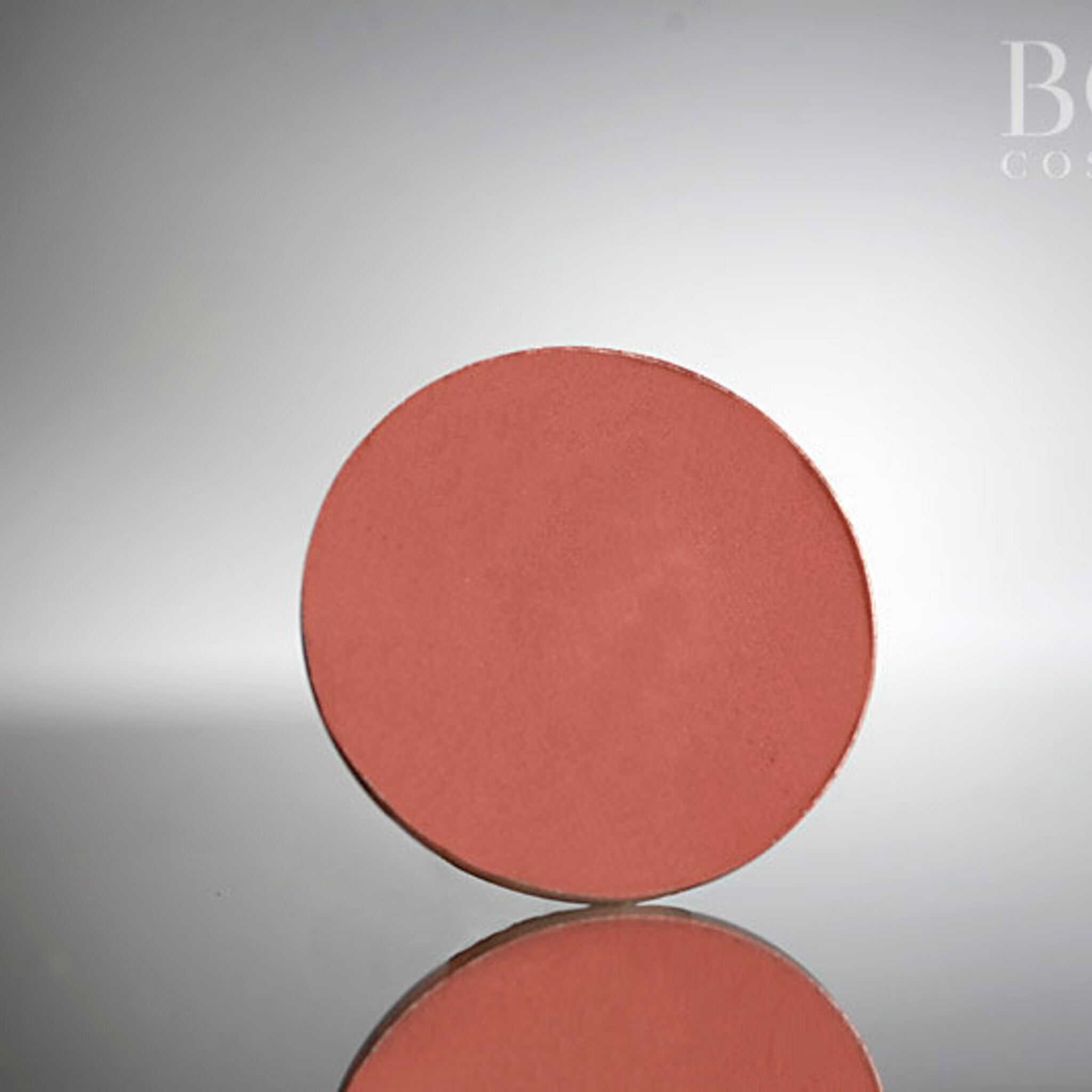 Single pressed matte eyeshadow pan in deep red wine shade with smooth pigment surface