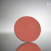 Single pressed matte eyeshadow pan in deep red wine shade with smooth pigment surface